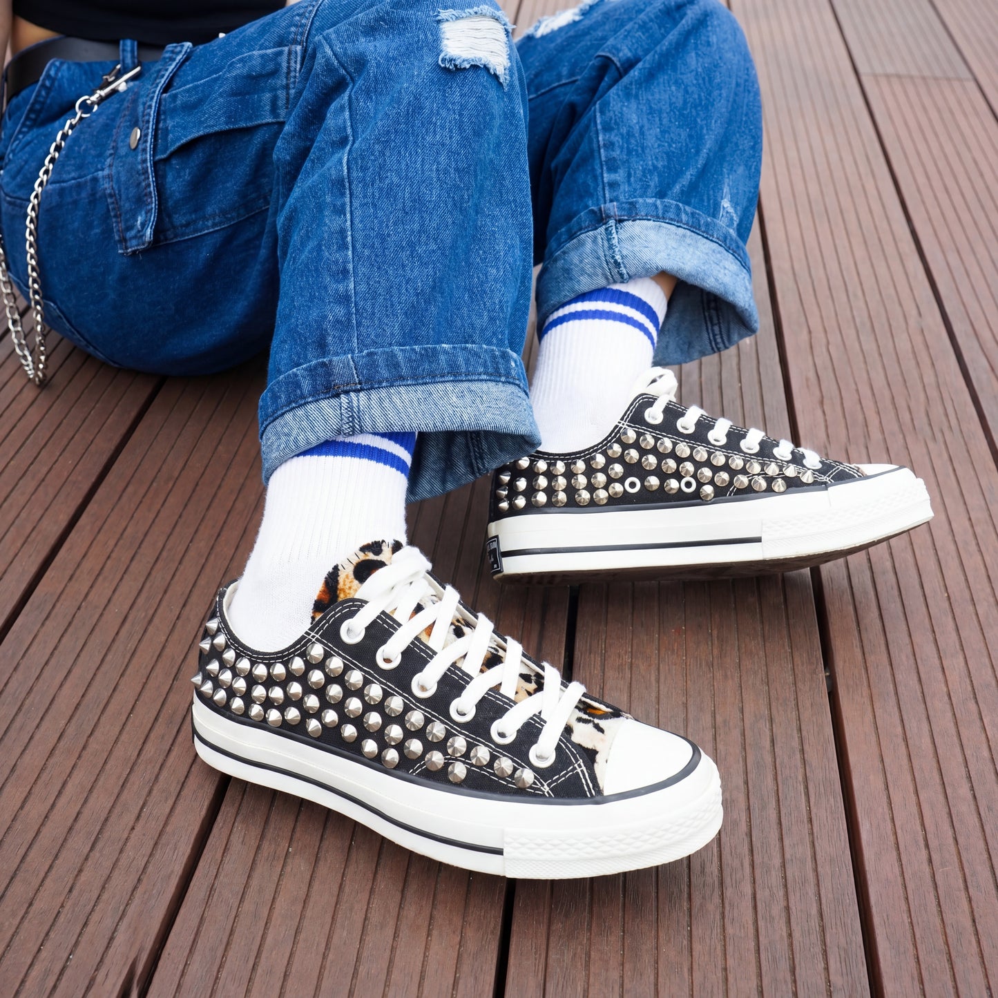 Black and white studded sneakers styled with denim jeans and striped socks
