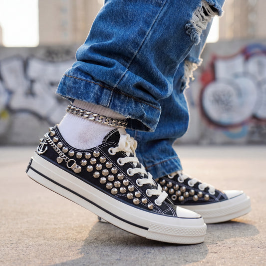 Black studded low top Converse sneakers with silver anchor charms